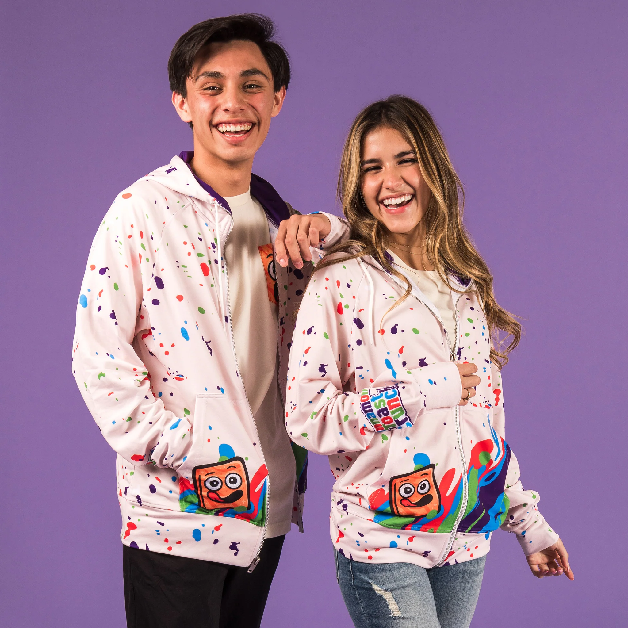Two people wearing Head-Turning Hoodie white hoodie with colorful blobs and cinnamon toast crunch smile