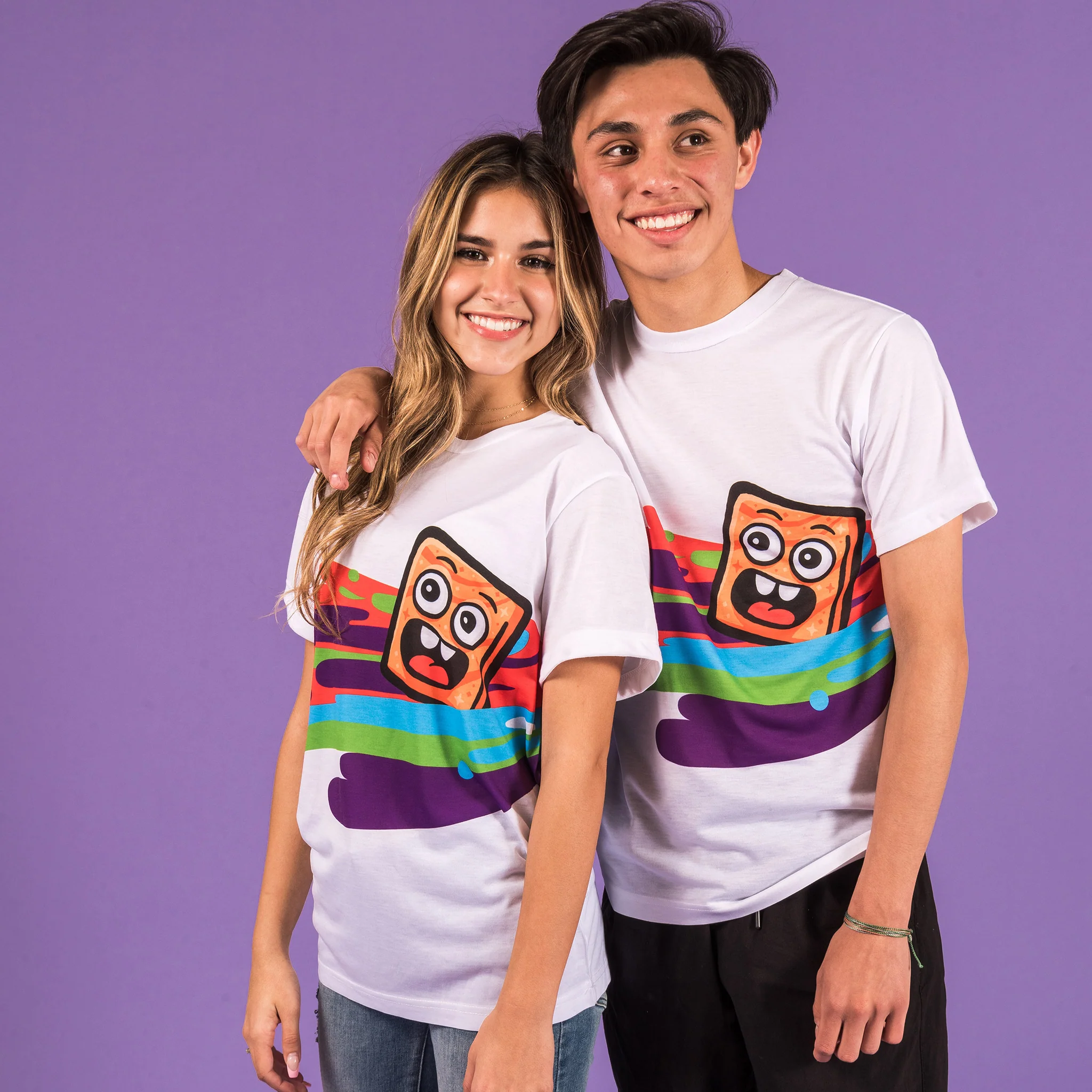 People wearing Cinnamoji Swirl Tee white tee with colorful blobs and cinnamon toast crunch smile